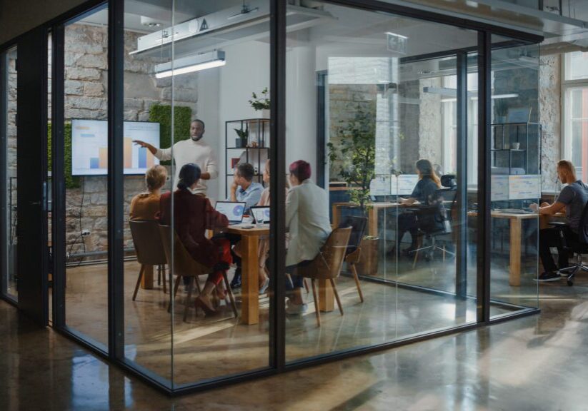 Office Conference Room Meeting: Male Chief Executive Talking to a Diverse Team of Professional Businesspeople. Creative People Listen to CEO Discuss Design, Data Analysis, Plan Marketing Strategy